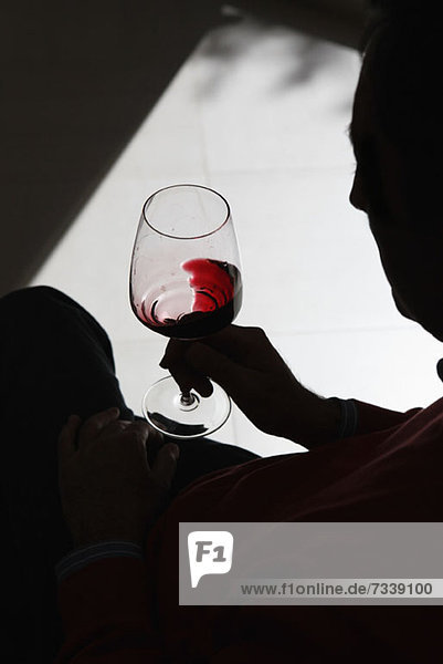 Eine Person mit Silhouette  die Wein in einem Weinglas wirbelt.