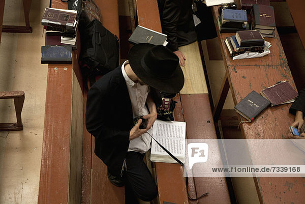 Jewish man holding tefillin in synagogue