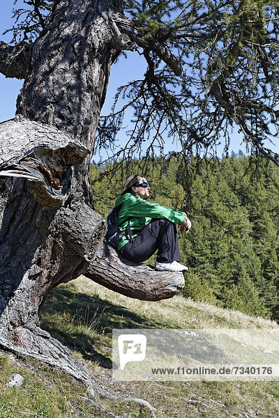 Wanderin sitzt auf abgesägtem Ast  Bürgeralm Aflenz  Bruck an der Mur  Steiermark  Österreich  Europa