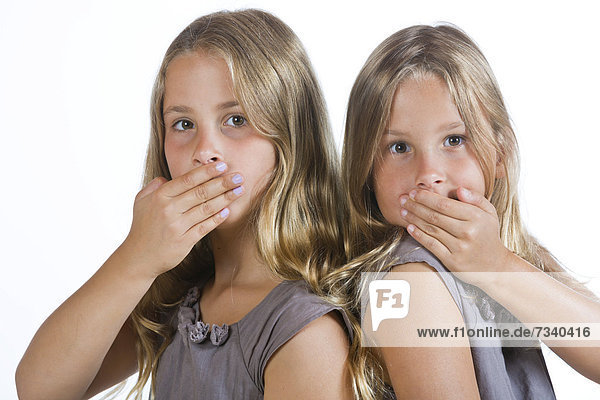 Twin girls  9  holding their mouths closed