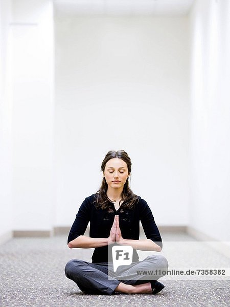 woman sitting on the floor in her workplace meditating