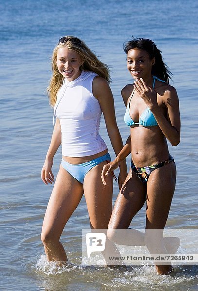 Two young women wading in the water on the beach