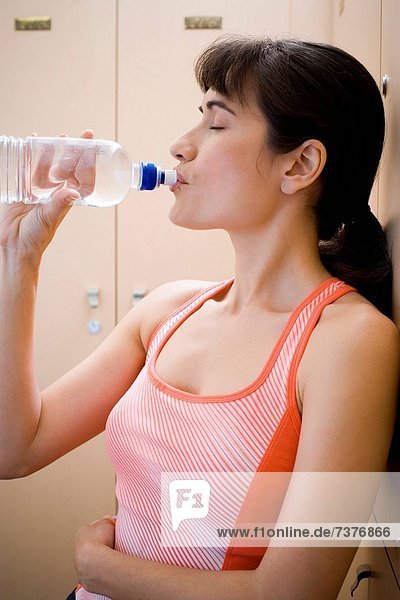 Profile of a young woman drinking water from a water bottle