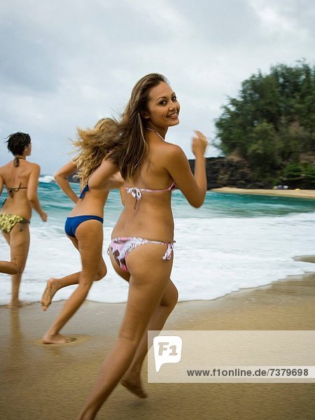 Three young women running on the beach