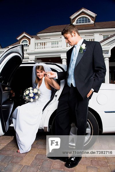Young man holding his brides hand and exiting a car