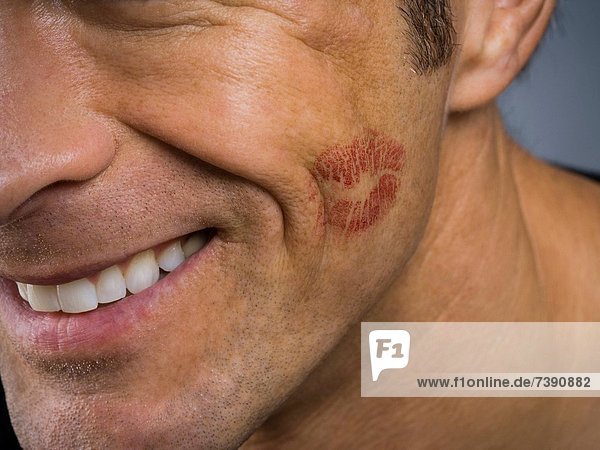 Closeup of man smiling with lipstick kiss on cheek