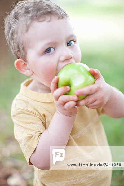 Boy eating apple outdoors