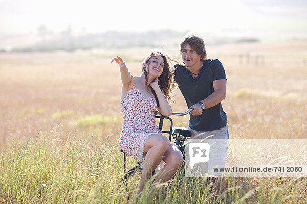 Paar spielt auf dem Fahrrad im hohen Gras