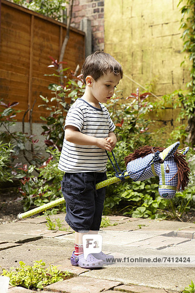 Boy playing with toy horse in garden