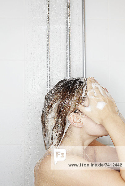 Frau wäscht sich die Haare unter der Dusche