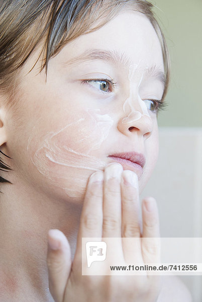 Mädchen reibt Feuchtigkeitscreme auf ihr Gesicht
