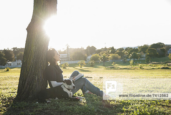 Frau entspannt sich mit Hund im Park