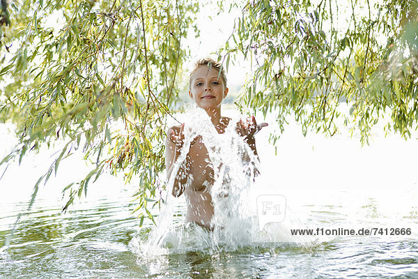 Nude woman splashing in river