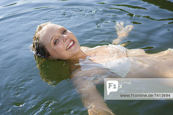 Smiling woman floating in still lake