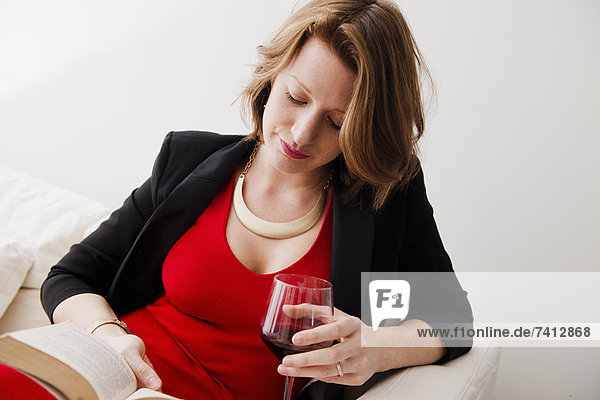 Woman with wine reading book on sofa