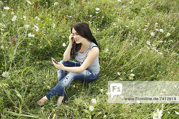 Woman listening to headphones in grass