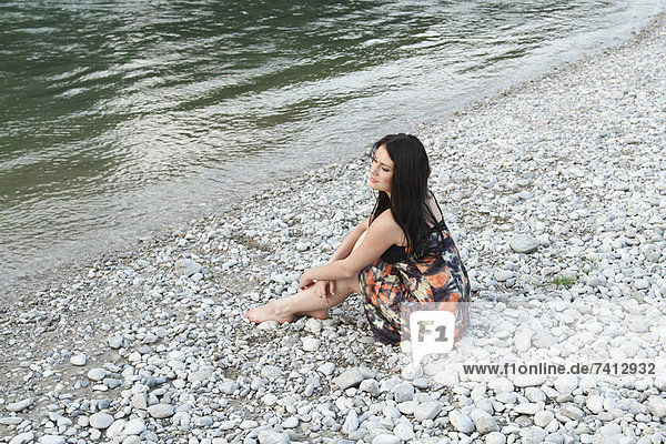 Woman sitting on rocky beach