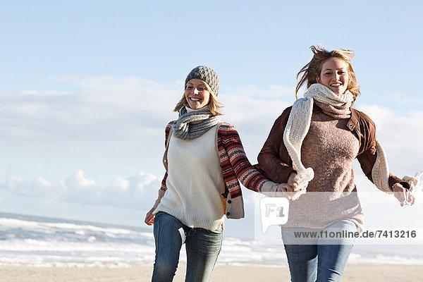 Lächelnde Frauen beim Laufen am Strand