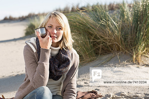 Woman drinking from thermos on beach