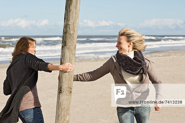 Lächelnde Frauen spielen am Strand