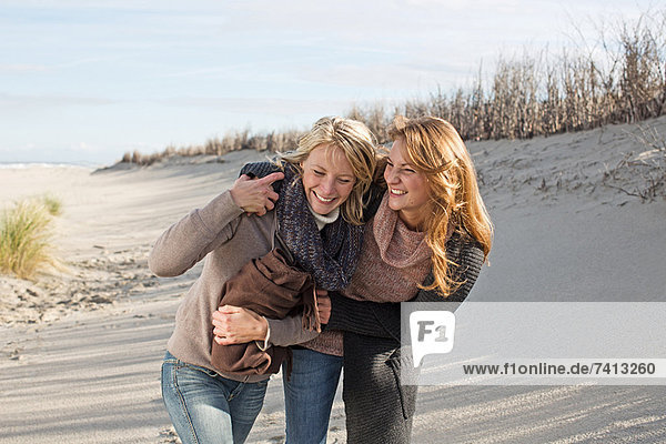 Lächelnde Frauen  die am Strand spazieren gehen