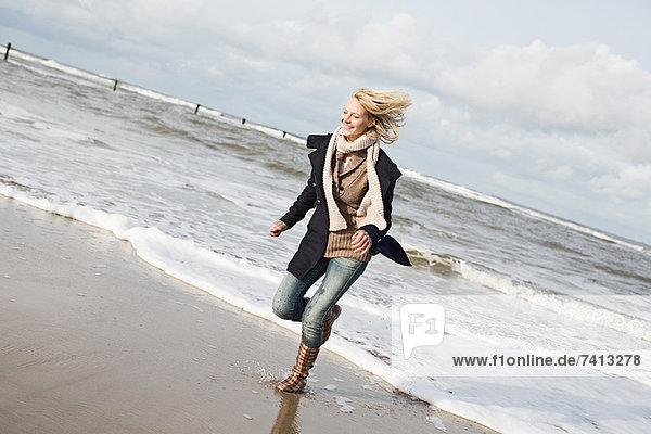 Lächelnde Frau am Strand laufend