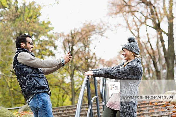 Mann fotografiert Freundin im Park