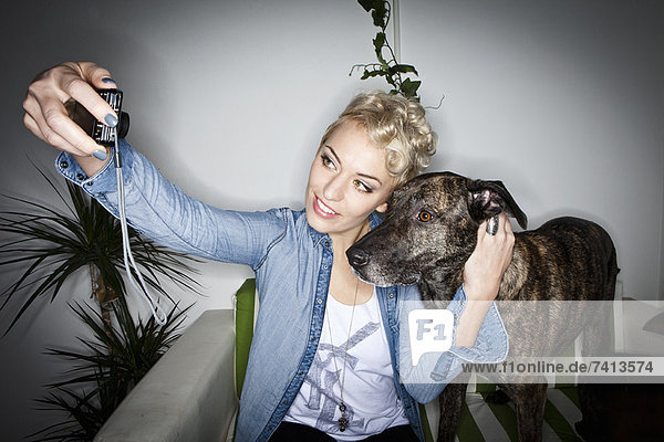 Lächelnde Frau beim Fotografieren mit Hund
