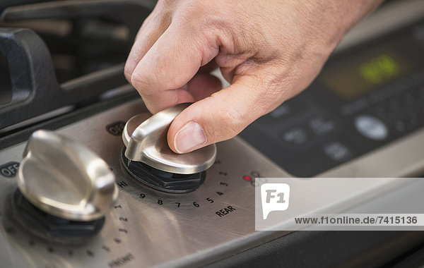 Close-up of hand adjusting stove burner