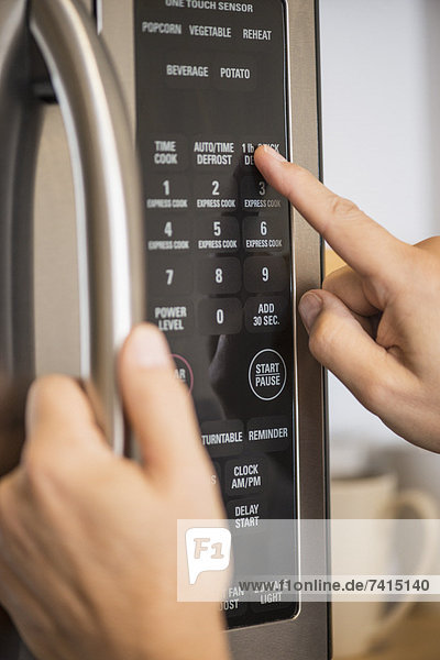 Close-up of hand using microwave oven