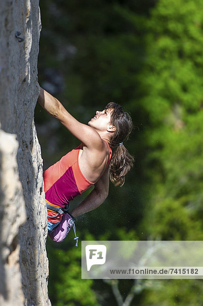 A close up view on Nina Caprez reaching to her chalk bag during a demanding limestone climb.