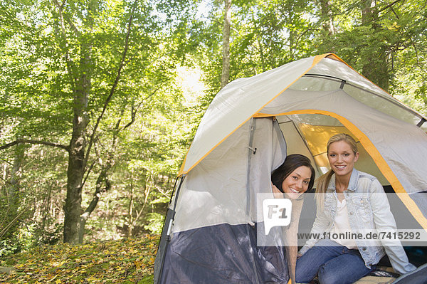 Two women sitting in tent in forest