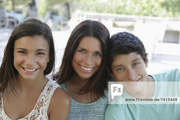 Outdoor portrait of smiling mother with daughter (12-13) and son (14-15)