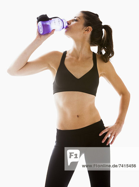 Young woman drinking water after exercising  studio shot