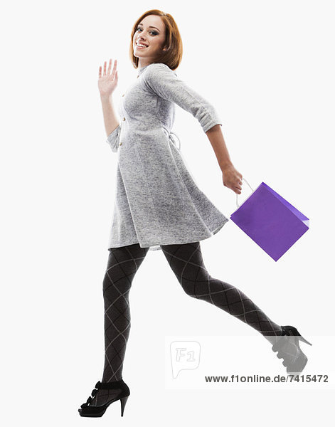 Young woman running with shopping bag  studio shot
