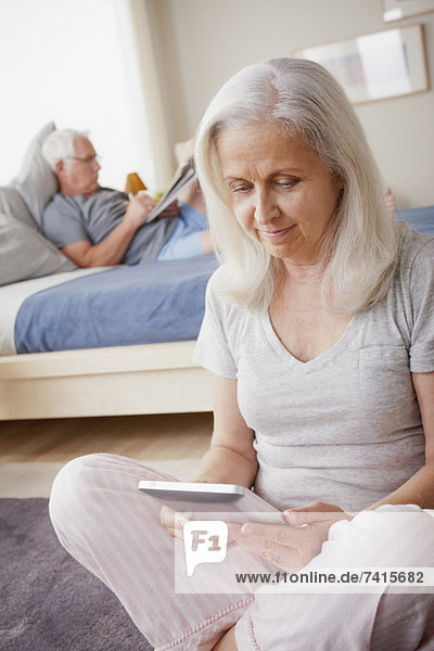 Senior woman holding photo frame  man sitting on bed in background