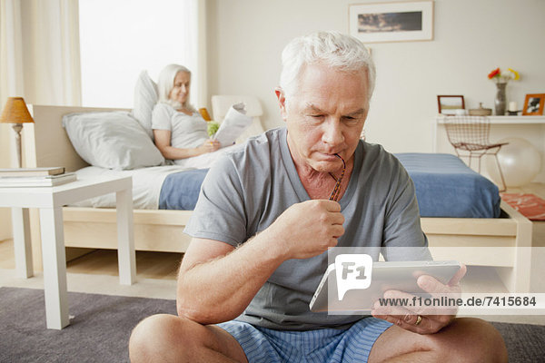 Senior man holding photo frame  woman sitting on bed in background