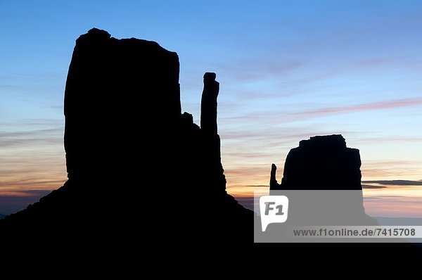 The famous Mittens are silhouetted at sunrise in Monument Valley AZ.