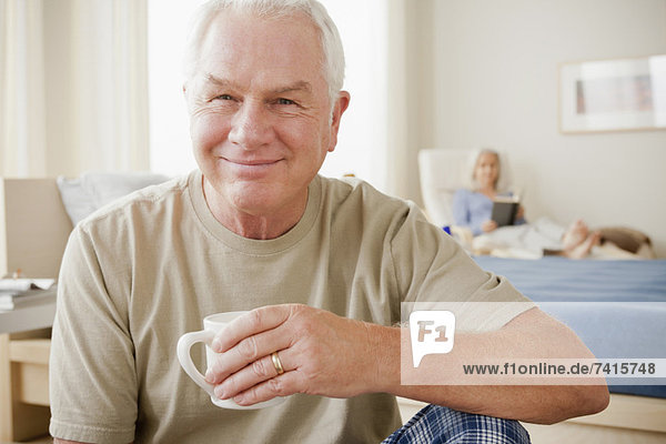 Senior man holding coffee cup and smiling