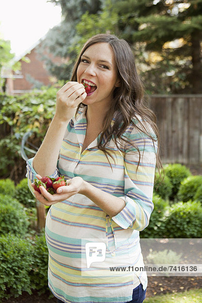 Portrait of pregnant mid adult woman eating strawberries
