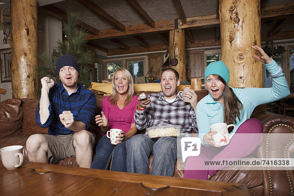 Friends watching tv in log cabin