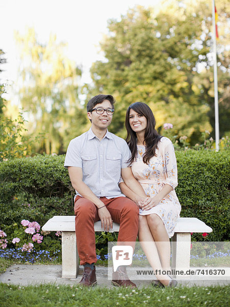 Portrait of couple sitting on bench in park
