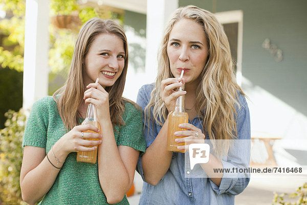 Portrait of two friends drinking soda through straw