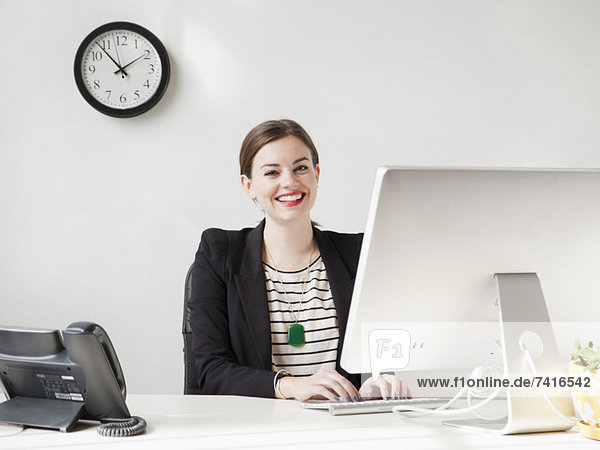 Studio shot portrait of young woman working on computer and smiling