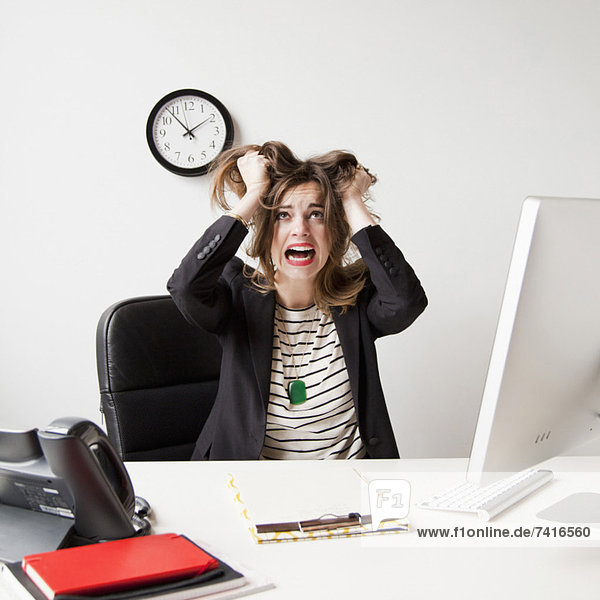 Studio shot of young woman working in office and tearing her hair out