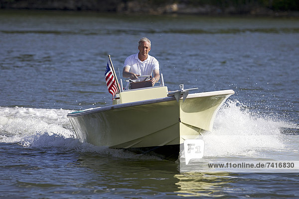 A middle-aged man drives his newly restored power boat along the scenic coast of Maine.