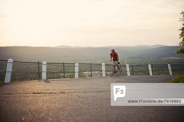 A female cyclist takes in the view as she nears the top of a mountain road in New England.