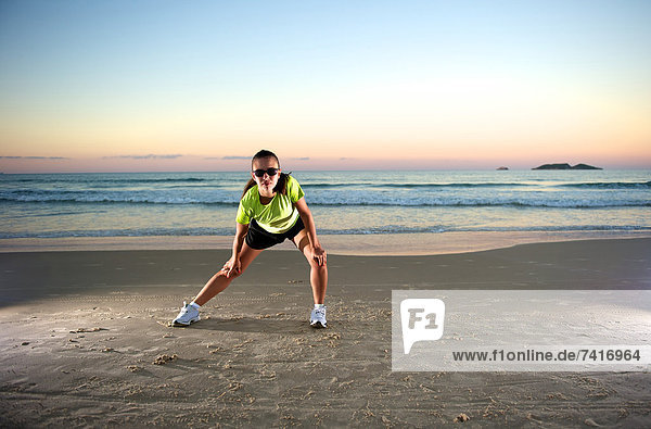 Woman doing some sport exercises on the beach at sunset.
