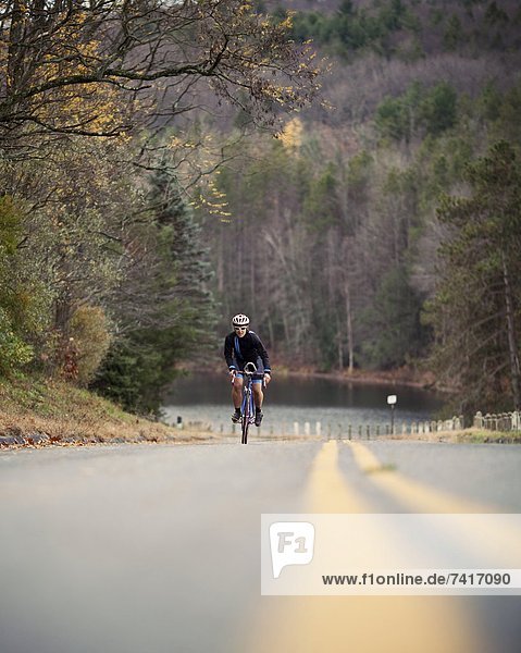 A female cyclist sprints up a hill while on a bike ride.