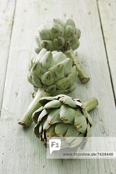 Three artichokes on a wooden surface